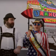 Two men stand in front of "Uranus Fudge Factory" sign